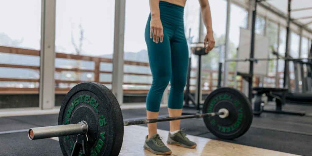 Personne dans une salle d'entraînement qui fait de la musculation avec une barre libre