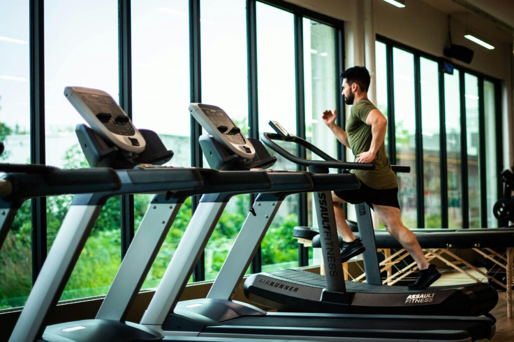 Personne qui cours sur un tapis roulant dans une salle d'entraînement vitrée.